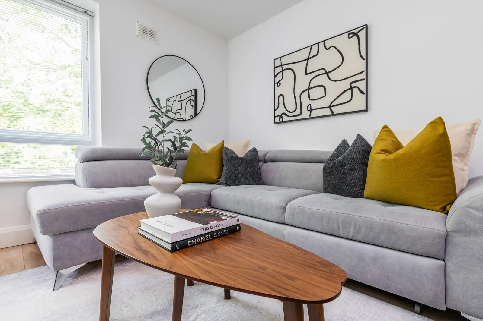 Styled living room of an EirStay managed Dublin apartment with grey corner sofa, ready for corporate letting