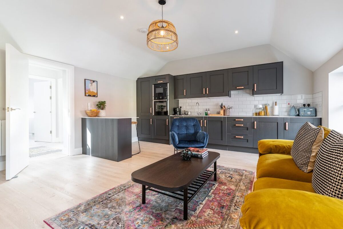 Open plan layout with kitchen island and rattan pendant in EirStay corporate short stay apartment Camden Street Dublin 2