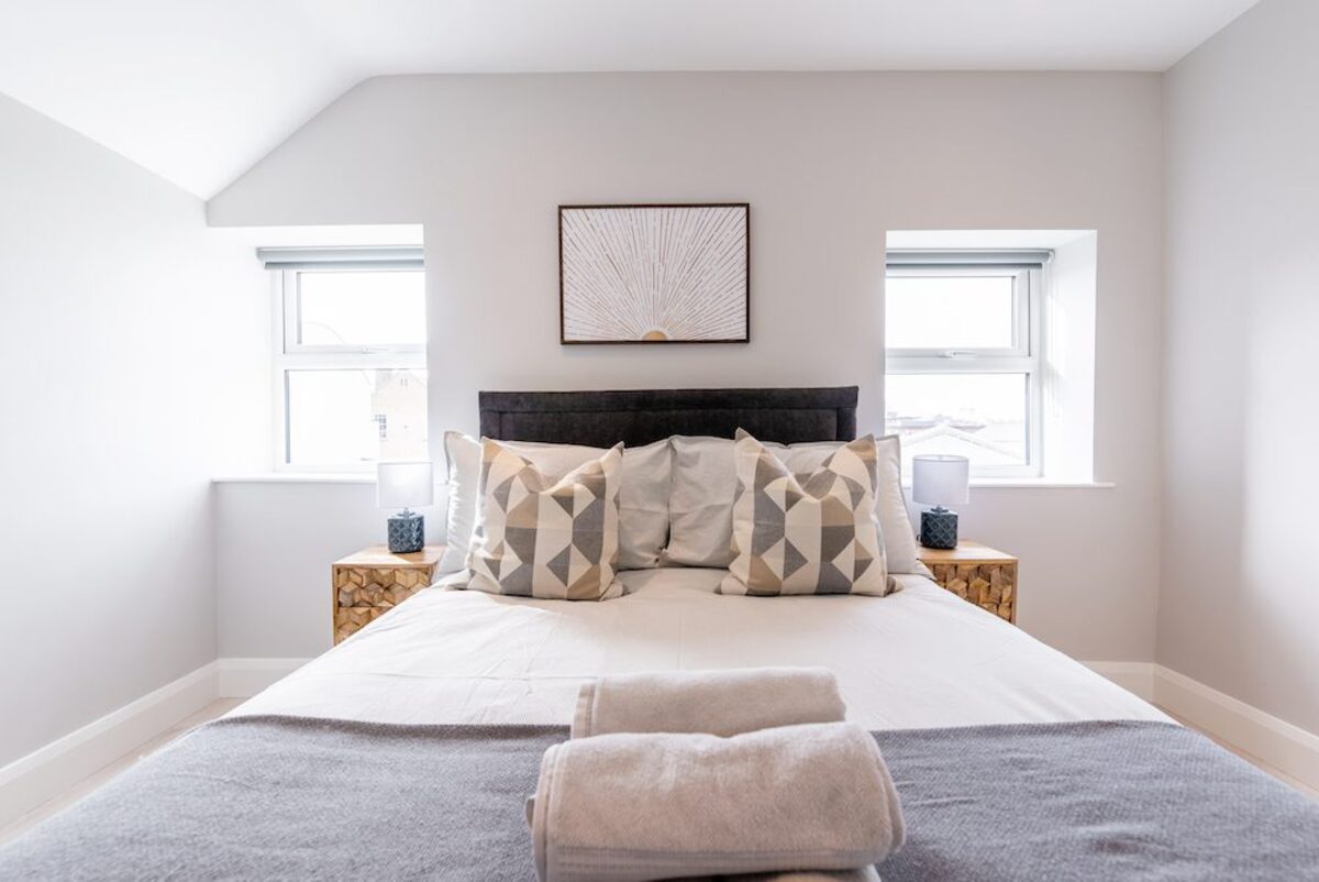 King-size bed with geometric cushions sunburst wall art and fresh towels in EirStay serviced apartment Camden Street Dublin 2