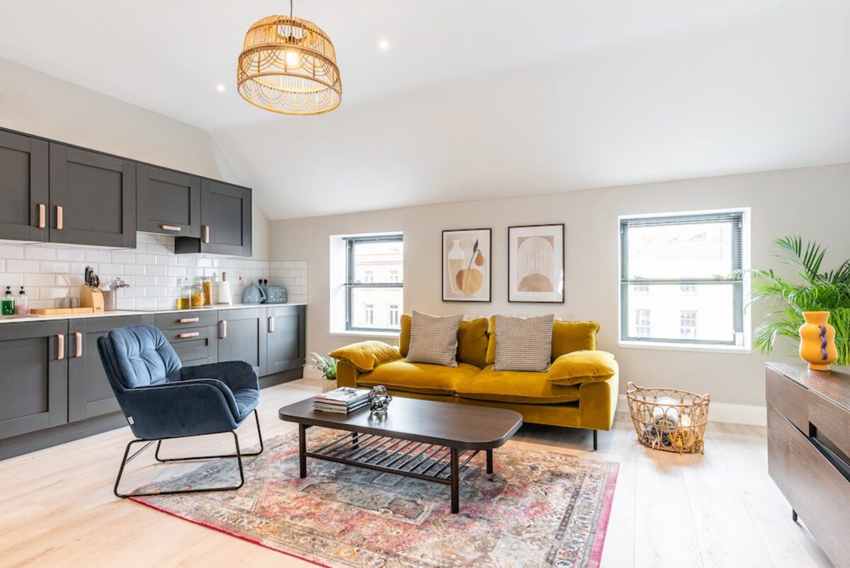 Spacious open plan living area with rattan pendant light and persian rug in EirStay serviced apartment Camden Street Dublin 2