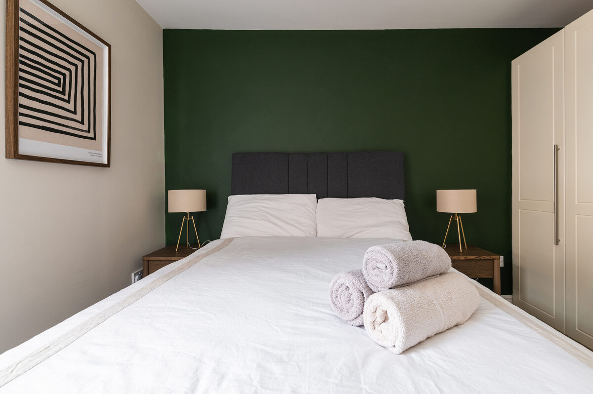 Master bedroom with double bed and green feature wall in EirStay corporate short stay serviced apartment Dublin 4