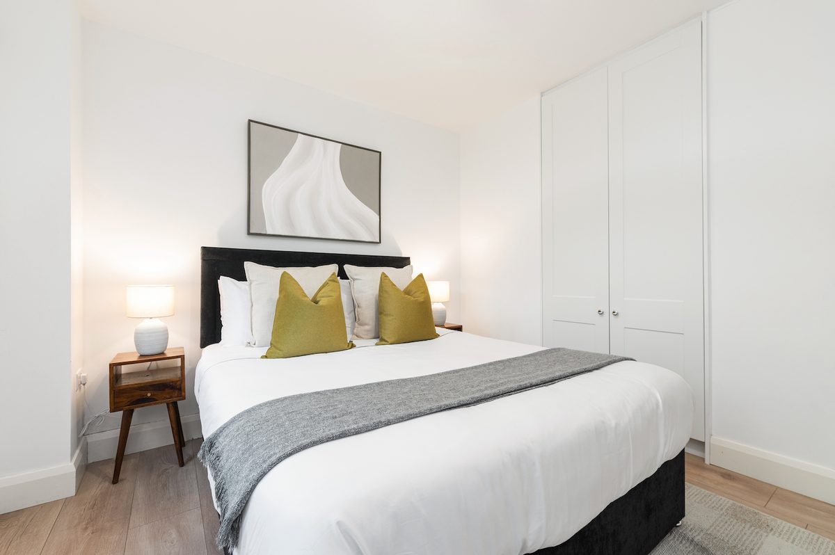 Double bedroom with upholstered headboard, bedside lamps and fitted wardrobe in EirStay Islandbridge one-bedroom serviced apartment Dublin 8