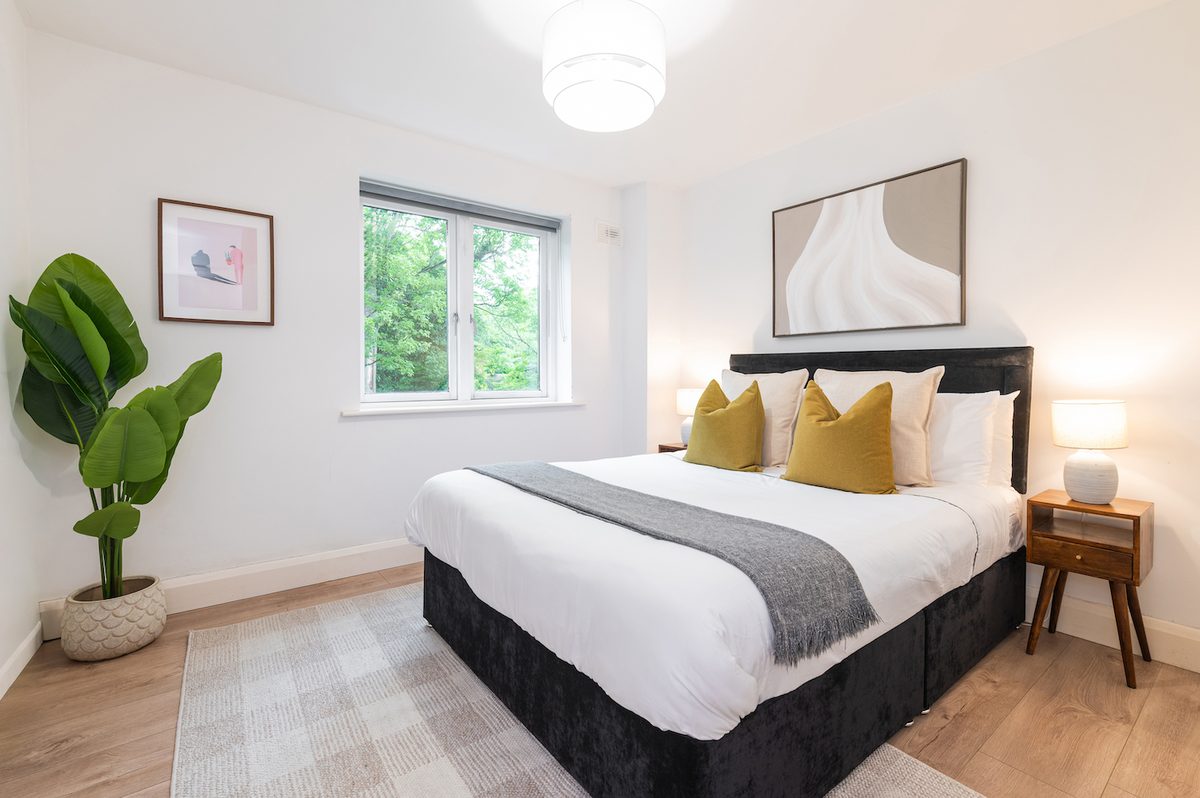 Double bedroom with bright window, house plant and bedside tables in EirStay Islandbridge corporate apartment Dublin 8
