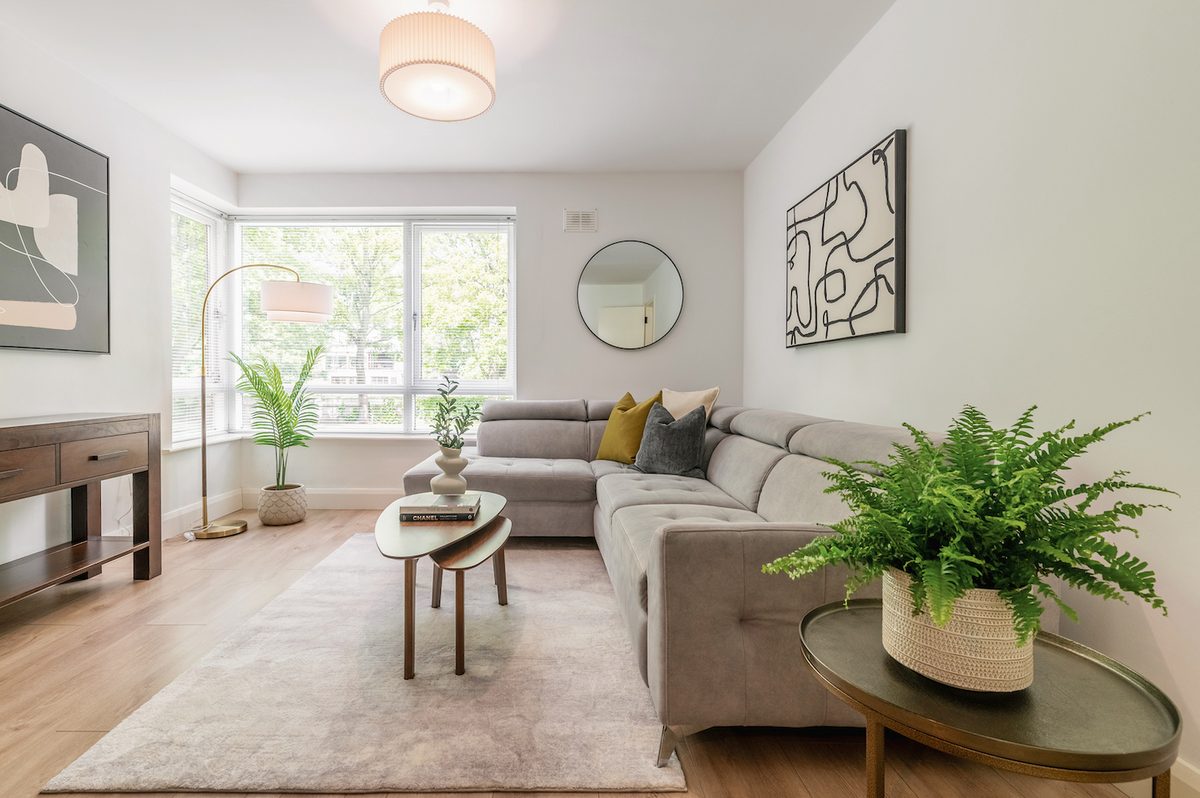 Spacious lounge with corner sofa, nest of tables and floor-height windows with tree views in EirStay Islandbridge corporate apartment Dublin 8