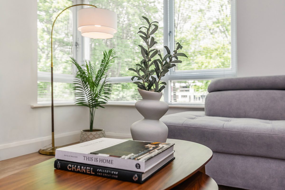 Sitting room with corner sofa, floor lamp and leafy garden outlook in EirStay Islandbridge serviced apartment Dublin 8