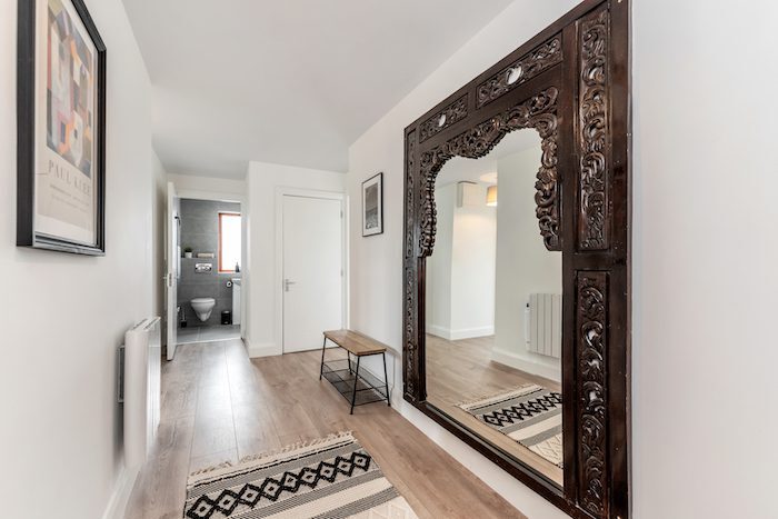 Hallway with ornate carved wooden full-length mirror geometric rug and Paul Klee print in EirStay corporate accommodation Kilmainham Dublin 8