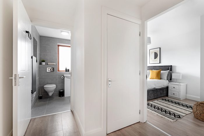 Hallway connecting grey tiled bathroom and bedroom with king bed in EirStay serviced apartment Kilmainham Dublin 8