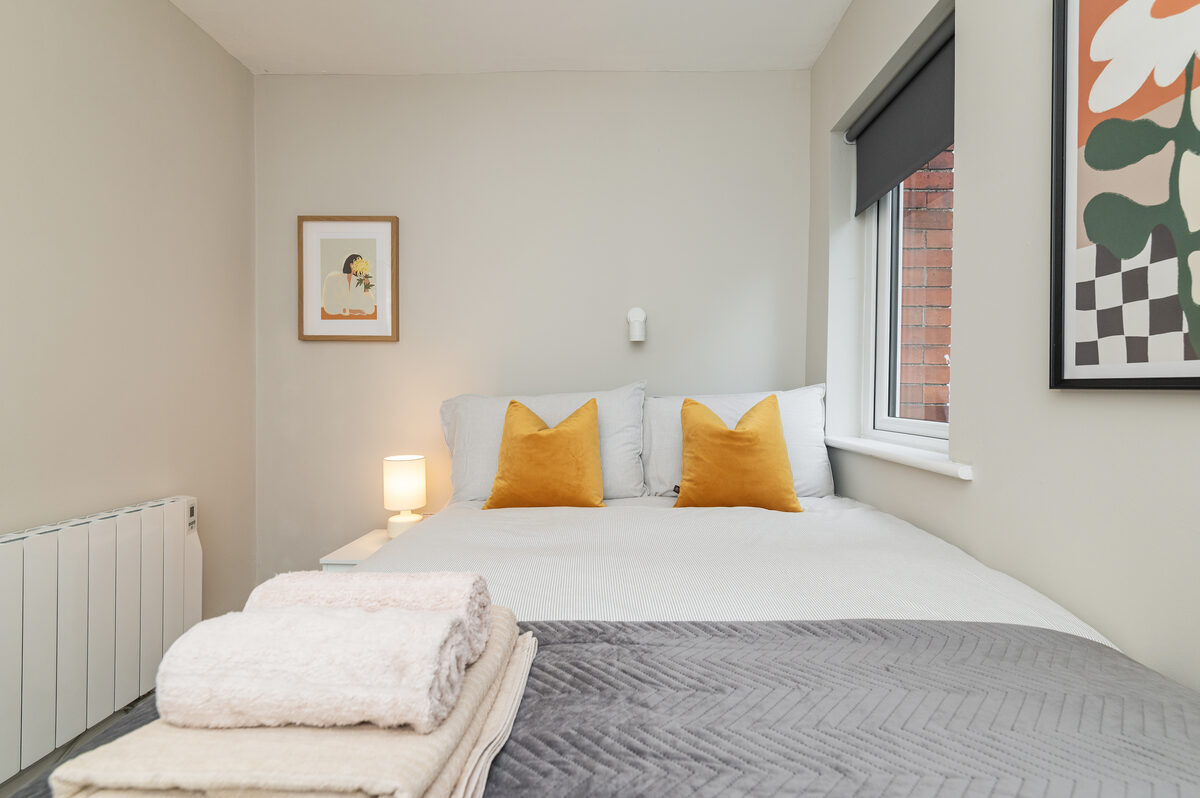 Second bedroom with mustard accent pillows and fresh towels in EirStay short-term corporate accommodation Ranelagh Dublin 6